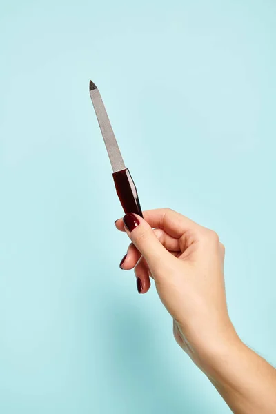 Oggetto foto di lima in mano di giovane donna sconosciuta con smalto su sfondo blu — Foto stock