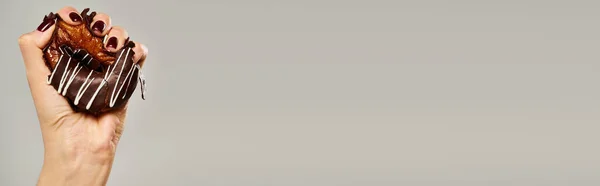 Donna sconosciuta con smalto spremitura dolce ciambella con glassa marrone su sfondo grigio, banner — Foto stock