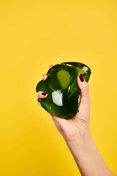Object photo of delicious green jello in hand of unknown female model on vibrant yellow backdrop — Stock Photo