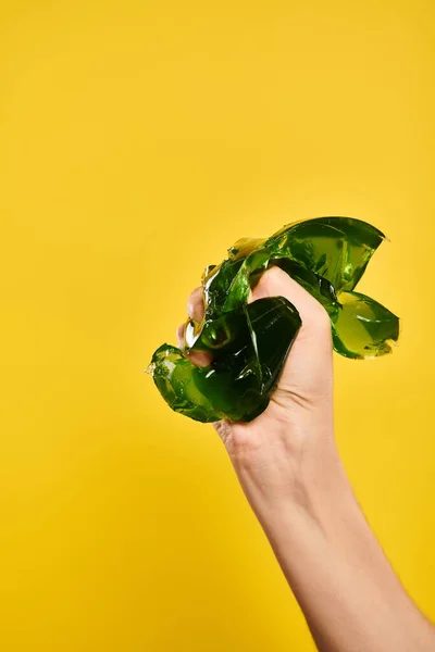 Unknown young lady with nail polish squeezing green delicious jelly in her hand on yellow background — Stock Photo