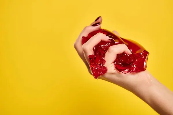 Unbekanntes weibliches Modell, das auf leuchtend gelbem Hintergrund rote köstliche Marmelade in der Hand hält — Stockfoto
