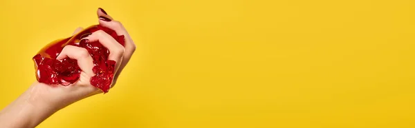 Modèle féminin inconnu serrant la gelée savoureuse rouge dans sa main sur fond jaune vif, bannière — Photo de stock