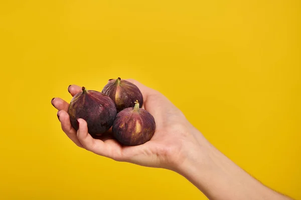 Object photo of delicious organic figs in hand of young unknwon woman on vibrant yellow backdrop — Stock Photo