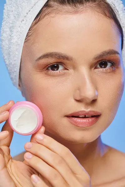 Close up portrait of woman with perfect face and towel on head with jar of cosmetic cream on blue — Stock Photo
