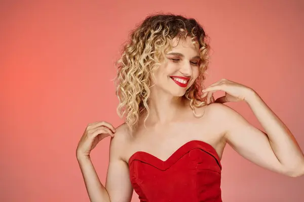 Cheerful elegant woman with red lips and top posing with closed eyes on pink and yellow backdrop — Stock Photo