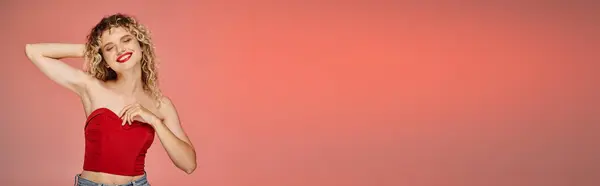 Charming woman with bold makeup in red top smiling with closed eyes on pastel backdrop, banner — Stock Photo