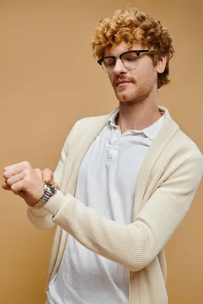 Beau jeune homme en lunettes regardant montre-bracelet sur beige, style vieux argent aristocratique — Photo de stock