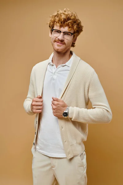 Joyful redhead man in eyeglasses and old money style outfit smiling at camera on beige backdrop — Stock Photo