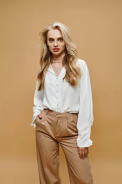 Confident blonde woman trendy clothes posing with hand in pocket on beige, old money style fashion — Stock Photo