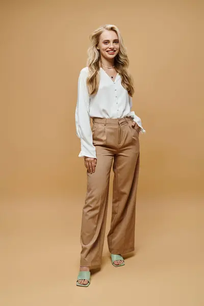 Full length of young trendy woman in white blouse and pants on beige, timeless classic fashion — Stock Photo
