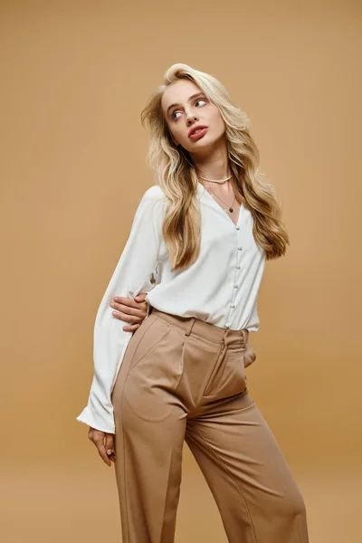 Sensual blonde woman in old money style attire looking away on beige backdrop, classic fashion shoot — Stock Photo