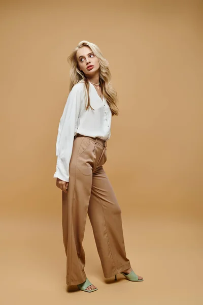 Full length of elegant blonde woman in trendy classic casual attire looking away on beige, banner — Stock Photo