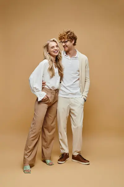 Full length of cheerful couple in casual clothes smiling on beige, timeless classic fashion — Stock Photo