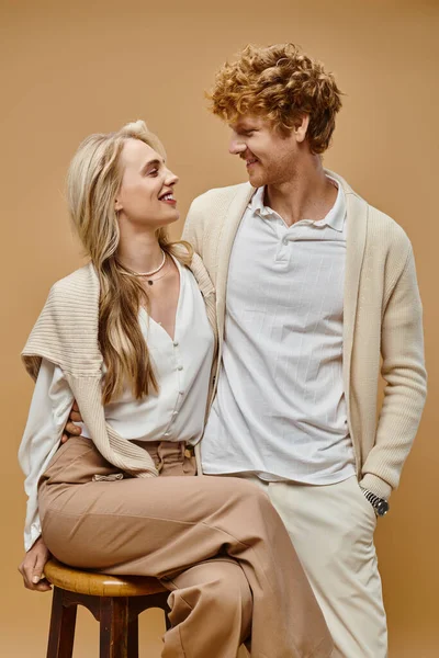 Elegant blonde woman and redhead man smiling at each other on beige backdrop, old fashion style — Stock Photo