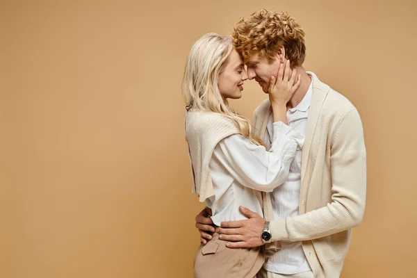 Side view of fashionable couple embracing face to face with closed eyes on beige, old money style — Stock Photo