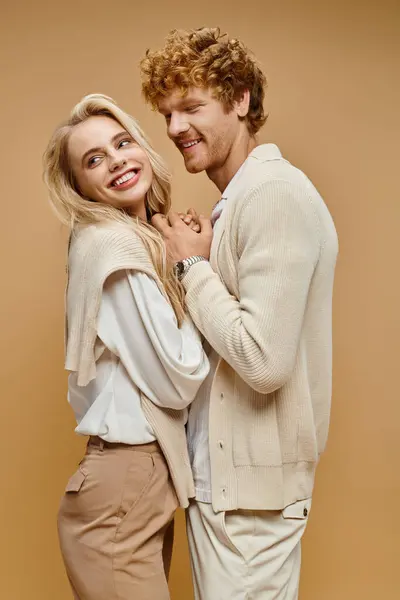 Alegre joven pareja en moda viejo dinero estilo traje de la mano en beige, moda atemporal - foto de stock