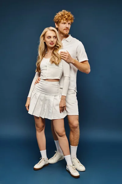 Full length of young fashionable couple  in white trendy attire on blue backdrop, old money style — Stock Photo