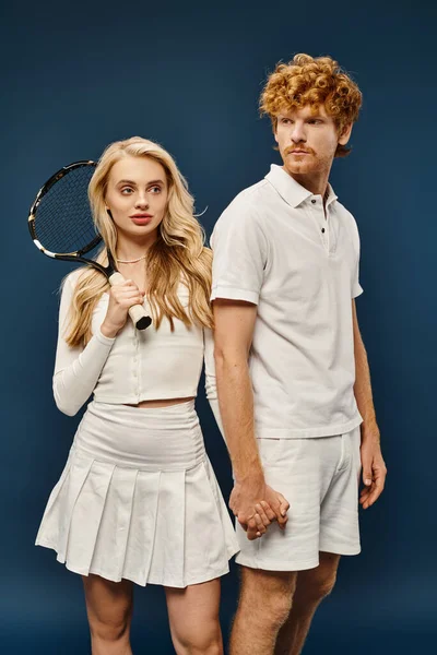 Модный рыжий мужчина в белой одежде рядом с женщиной с теннисной ракеткой на синем, старом стиле денег — стоковое фото