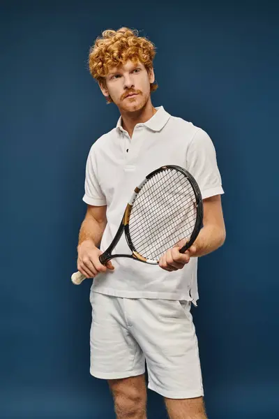 Homme rousse aristocratique en polo blanc t-shirt et short avec raquette de tennis regardant loin sur bleu — Photo de stock