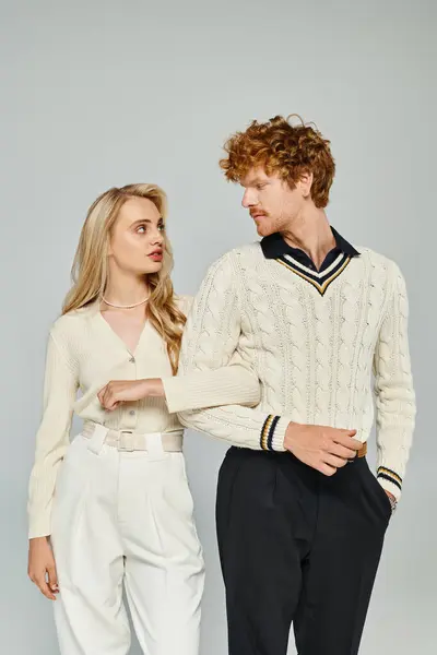 Old money style fashion, trendy young couple looking at camera while walking on grey backdrop — Stock Photo