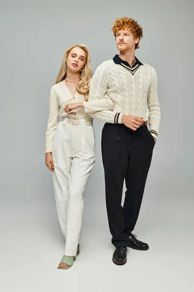Longitud completa de la joven pareja de estilo de dinero viejo caminando sobre fondo gris en el estudio, concepto de moda - foto de stock