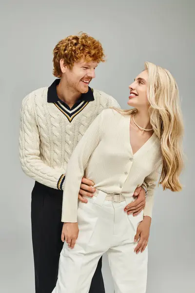 Fröhliches und trendiges Paar, das sich vor grauem Hintergrund anschaut, Modekonzept im alten Geldstil — Stockfoto