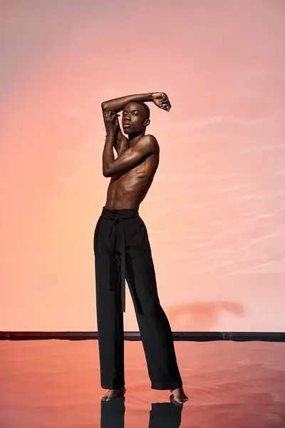 Красивий без сорочки афроамериканський чоловік стоїть і дивиться на камеру в оточенні червоних вогнів — стокове фото