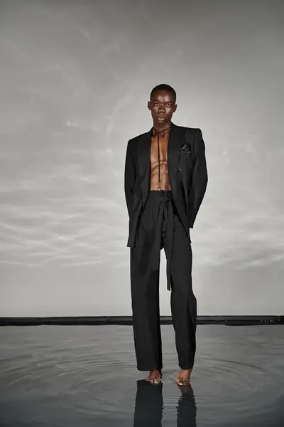 Fashionable african american man in unbuttoned black suit posing alluringly and looking at camera — Stock Photo