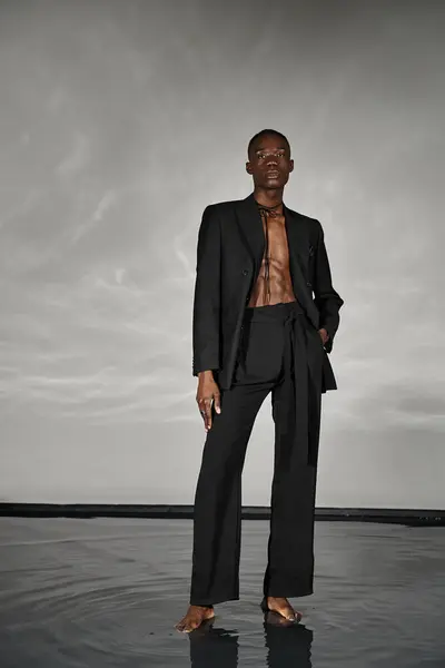Fashionable african american man in unbuttoned black suit posing alluringly and looking at camera — Stock Photo