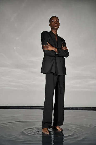 Charming african american man in unbuttoned black suit posing alluringly and looking at camera — Stock Photo
