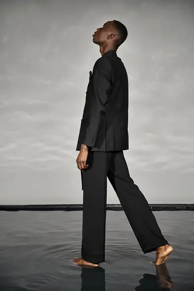 Charming stylish african american man in sexy unbuttoned suit posing on gray watery background — Stock Photo