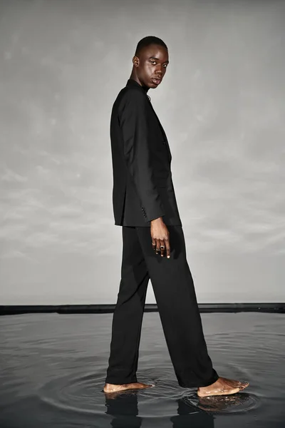 Charming african american man in unbuttoned black suit posing alluringly and looking at camera — Stock Photo