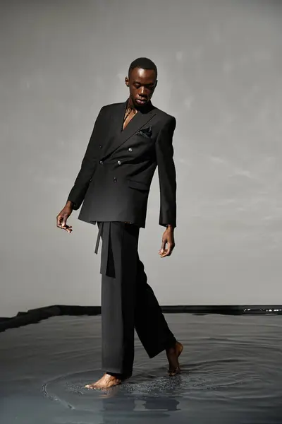 Handsome stylish african american man in sexy unbuttoned suit posing on gray watery background — Stock Photo