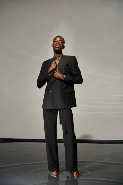Charming african american man in unbuttoned black suit posing alluringly and looking at camera — Stock Photo