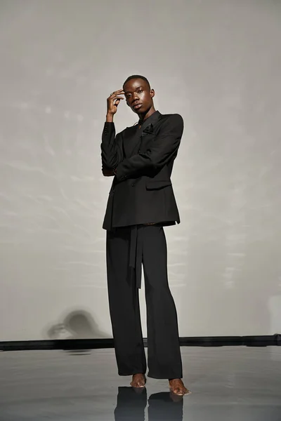 Handsome african american man in unbuttoned black suit posing alluringly and looking at camera — Stock Photo