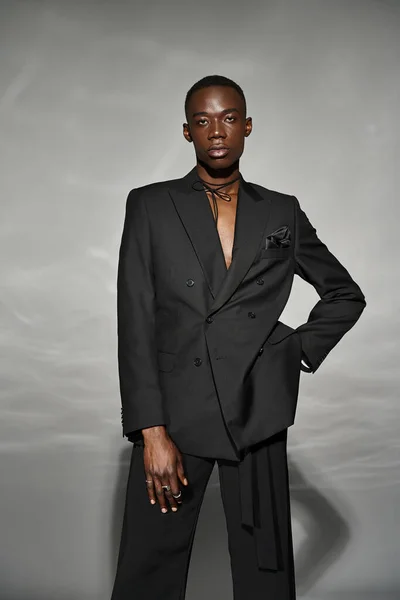 Engaging african american man in unbuttoned black suit posing alluringly and looking at camera — Stock Photo