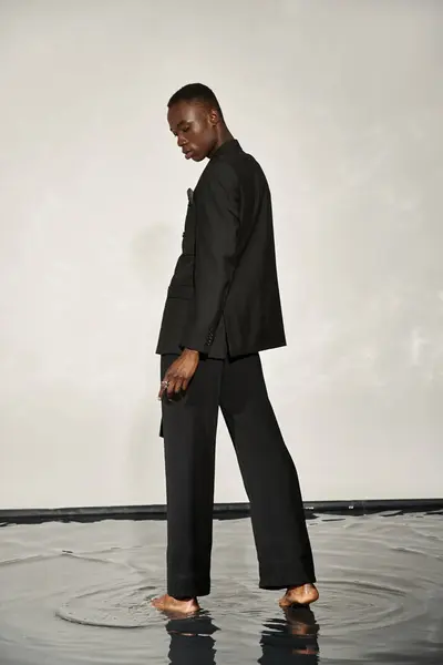 Good looking african american man in stylish black suit posing alluringly on watery background — Stock Photo