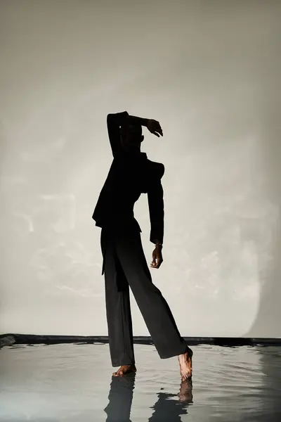Silhouette of stylish african american man posing barefoot in suit on watery backdrop in shadows — Stock Photo
