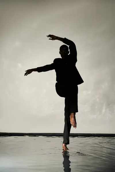 Silhouette of stylish african american man posing barefoot in suit on watery backdrop in shadows — Stock Photo