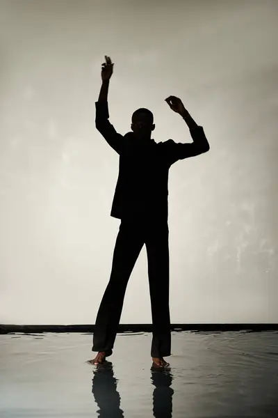 Silhouette of trendy african american man posing barefoot in suit on gray watery backdrop in shadows — Stock Photo