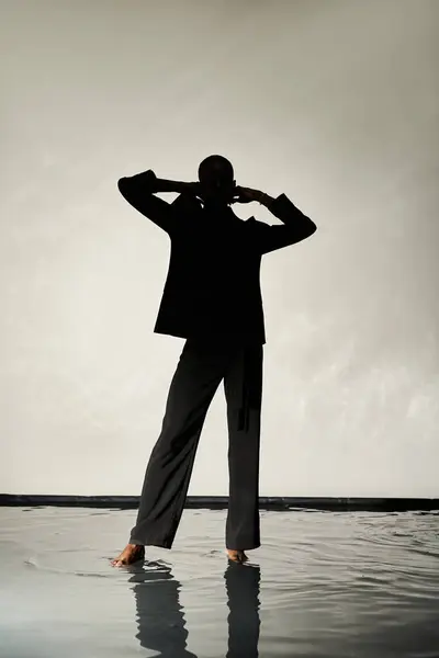 Silhouette of trendy african american man posing barefoot in suit on gray watery backdrop in shadows — Stock Photo