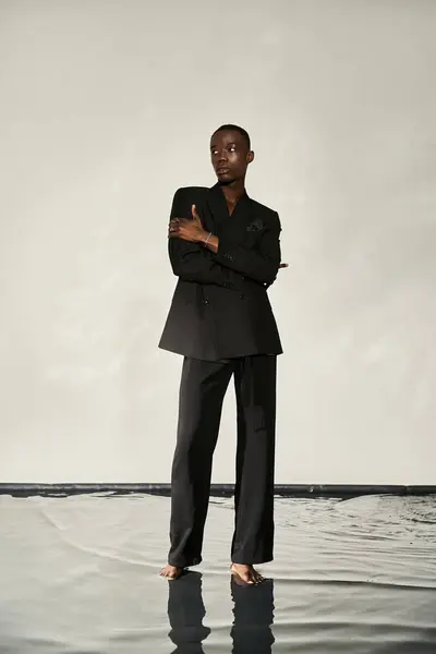 Good looking african american man in elegant black suit posing alluringly on watery background — Stock Photo