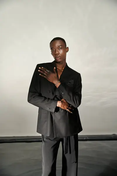 Handsome african american man in black sexy suit posing attractively on gray watery background — Stock Photo