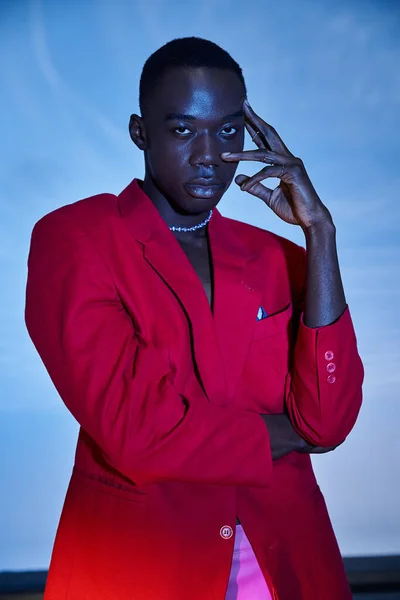 Handsome sexy african american man in red vivid blazer looking at camera on blue watery background — стоковое фото