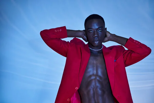Bello sexy africano americano uomo in rosso vivido blazer guardando la fotocamera su sfondo acquoso blu — Foto stock