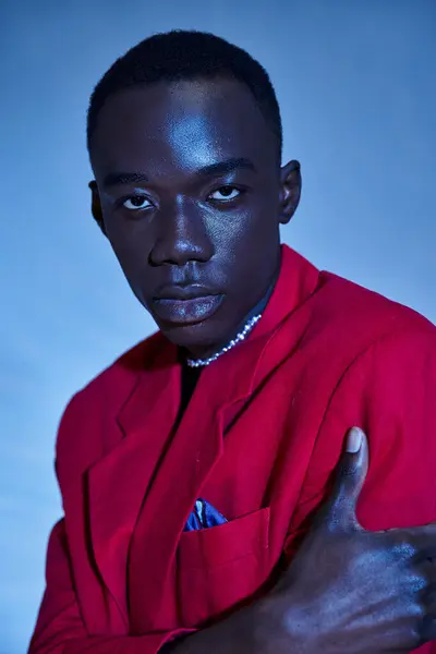 Trendy handsome african american man in red vibrant blazer posing on blue watery background — Stock Photo
