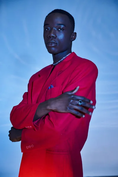 Appealing young african american man in red vibrant blazer posing on blue watery background — Stock Photo