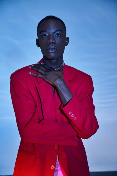 Fashionable young african american man in red vibrant blazer posing on blue watery background — Stock Photo