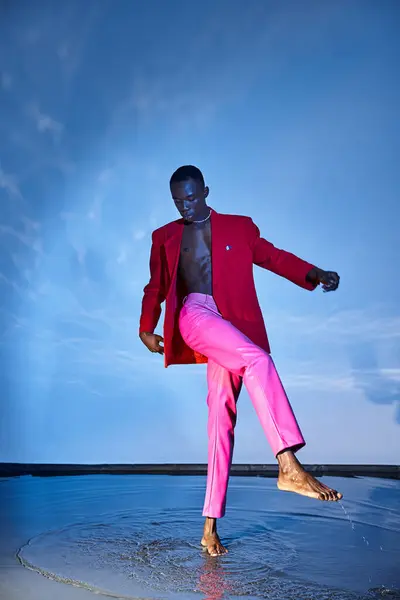 Stylish young african american man in pink pants and red blazer looking away on watery backdrop — Stock Photo