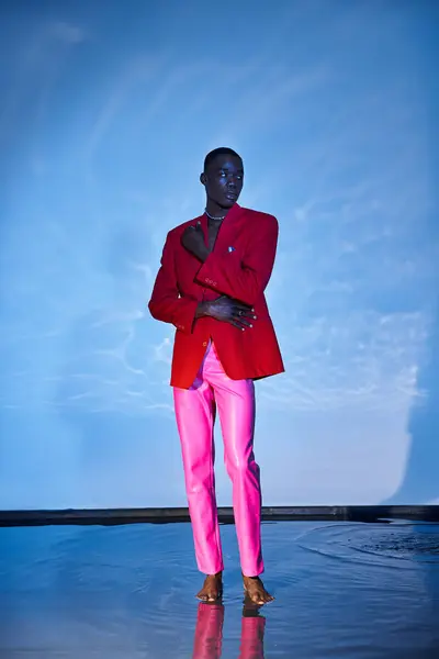 Fashionable african american man in pink pants and red blazer looking away on watery backdrop — Stock Photo